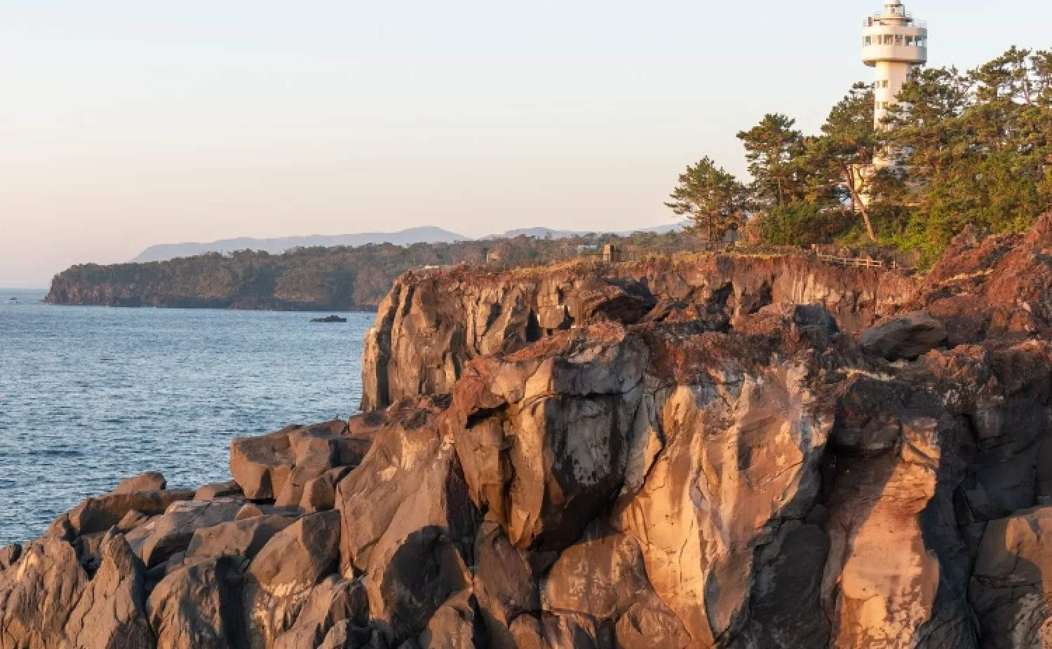 朝日に輝く岩壁と広がる相模湾の青